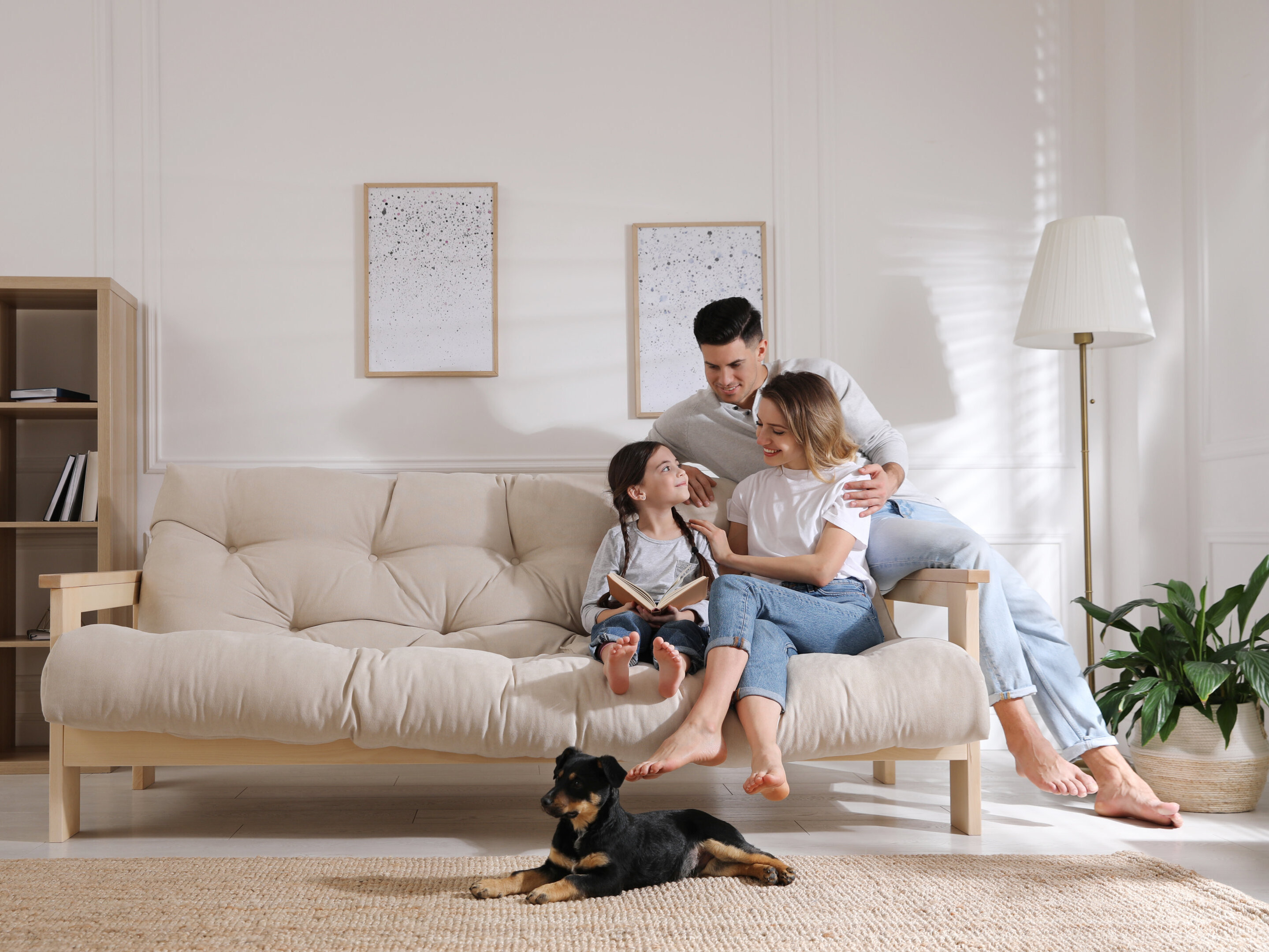 AdobeStock_433610564 Happy family on sofa and puppy in living room