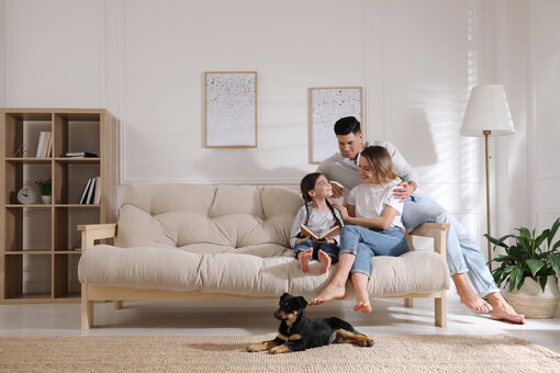 AdobeStock_433610564 Happy family on sofa and puppy in living room
