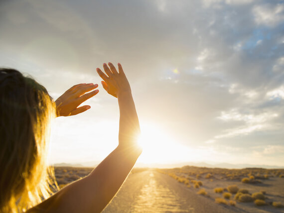 Hispanic woman shielding eyes from sun on remote road
