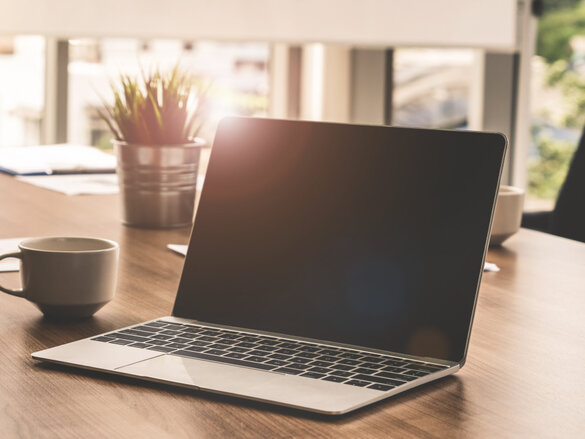 Laptop computer with opened lid on table in meeting room of office workspace.